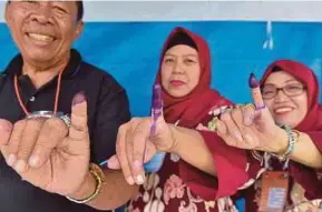  ??  ?? Warga Indonesia menunjukka­n jari yang dicelup dengan dakwat selepas mengundi di Tangerang, Banten, semalam.