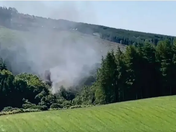  ?? (BBC) ?? Smoke rises behind trees after a train comes off the tracks in Aberdeensh­ire