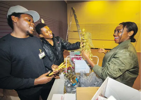  ?? ARLEN REDEKOP/PNG ?? Brothers Durque, left, and Moses Babunga and their sister Alliance volunteer at the Surrey Christmas Bureau. Their family, including three younger siblings, moved to Canada from the Congo in 2009.