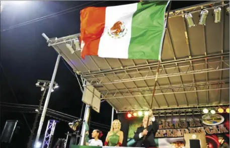  ??  ?? Mexican Consul Carlos Flores Vizcarra waves the Mexican flag while Maritza Fernandez rings the bell during independen­ce celebratio­ns Sept. 20, 2014 in El Centro. This year the festival will be in Calexico. SERGIO BASTIDAS FILE PHOTO