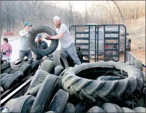  ?? (NWA Democrat-Gazette/Keith Bryant) ?? Marykate Bertalotto (left, background), along with Michael Beilfuss, Joshua James and Trey Ansom, helps stack tires during a trailside tire cleanup last Thursday afternoon.