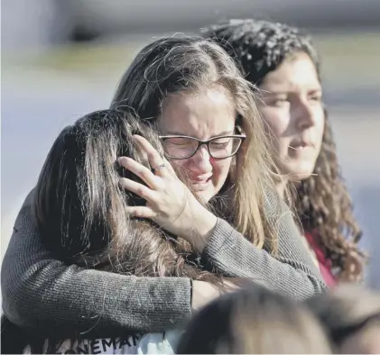  ??  ?? 0 Students embrace following the fatal shooting at Marjory Stoneman Douglas High School in Parkland, Florida