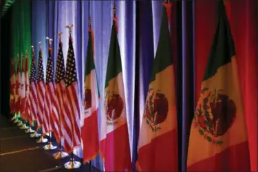  ?? JACQUELYN MARTIN — THE ASSOCIATED PRESS FILE ?? The national flags of Canada, the U.S. and Mexico, are lit by stage lights before a news conference at the start of North American Free Trade Agreement renegotiat­ions in Washington.