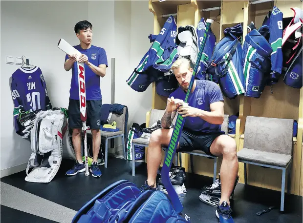  ?? JEFF VINNICK, NHLI VIA GETTY IMAGES ?? Goalies Taylor Sun, left, and Anders Nilsson tape their sticks before a Vancouver Canucks practice Tuesday at Mercedes-Benz Arena in Shanghai. The Canucks scored brownie points locally by signing Sun, who will be with the team for a pre-season series...