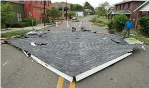  ?? The Sentinel-Record/Richard Rasmussen ?? ■ James Moore walks near a section of roof that was blown off of a nearby building Tuesday at the intersecti­on of Gulpha and Pleasant Street.