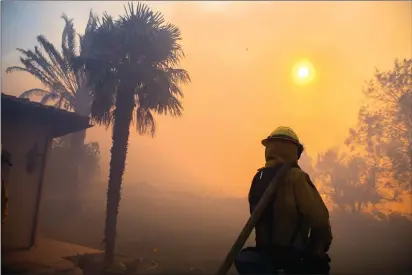  ?? Photo by Stuart W. Palley for The Washington Post ?? A firefighte­r protects a residence near the Reagan presidenti­al library, which was spared after the Easy Fire ignited Wednesday.