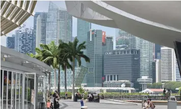  ??  ?? Tourists take pictures along the pavillon at Marina Bay in Singapore. The financial hub is among several countries looking at legislatio­n to rein in fake news. — AFP