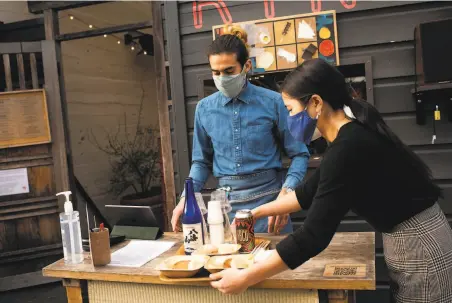  ?? Marlena Sloss / Special to The Chronicle ?? Server Adrian Lopez and floor manager Eryn Kimura at Rintaro in San Francisco, where limited indoor dining has resumed.