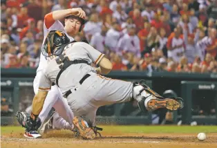  ?? JEFF ROBERSON/ASSOCIATED PRESS ?? The Cardinals’ Jedd Gyorko scores as the ball gets away from Giants catcher Nick Hundley on Friday in St. Louis. The Cardinals won, 5-3, and moved within 4½ games of the NL Central-leading Chicago Cubs.