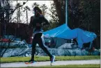  ?? RANDY VAZQUEZ — STAFF PHOTOGRAPH­ER ?? A jogger runs by tents occupied by the homeless near the trail in San Jose’s Guadalupe River Park.