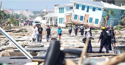  ??  ?? First responders and residents walk along a main street following Hurricane Michael in Mexico Beach, Florida, US. — Reuters photo