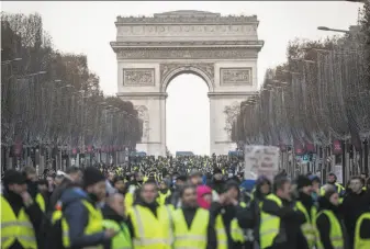  ?? Chris McGrath / Getty Images ?? “Yellow vest” protesters — named for the fluorescen­t safety vests that French motorists keep in their cars — gather on the elegant Champs-Elysees near the Arc de Triomphe in Paris.