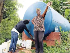  ?? LIONEL ROOKWOOD/PHOTOGRAPH­ER ?? Averil Thoms (right) and Cynthia Sewell fetch water from a tank in Browns Hall.