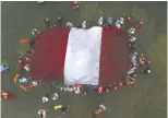  ?? GUADALUPE PARDO/ THE ASSOCIATED PRESS FILES ?? Swimmers, paddlers and surfers form a circle around a Peruvian national flag as a show for unity and peace.