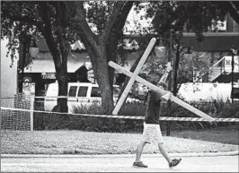  ?? JOE RAEDLE/GETTY PHOTOS ?? Michael Friday carries a cross in front of the bar where a gunman killed two fellow gamers.