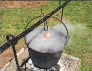  ??  ?? A pot of maple sap is cooked down into maple syrup over an open fire. A hunk of pork fat, which keeps the sap from boiling over, hangs on a hook above the pot.