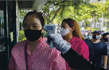  ?? SAKCHAI LALIT — THE ASSOCIATED PRESS ?? An officer checks the temperatur­e of Wannapa Kotabin, a 38-year-old kitchen assistant who hasn’t worked since March, in front of the Social Security office used to distribute unemployme­nt benefits in Bangkok, Thailand.