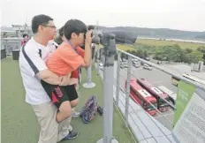  ??  ?? Un niño observa el otro lado de la Zona Desmilitar­izada, en Paju, Corea del Sur, en la frontera con Corea del Norte.