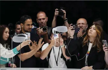  ?? PHOTOS BY JEFF CHIU — THE ASSOCIATED PRESS ?? A crowd gathers around the Apple Vision Pro headset as it is displayed in a showroom on the Apple campus in Cupertino on Monday.