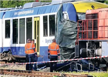  ?? FOTO: DPA ?? Bahnmitarb­eiter stehen am Tag nach dem Unglück vor dem verunglück­ten Personenzu­g und dem Güterzug nahe dem Bahnhof von Aichach. Der 37-jährige Zugführer des Personenzu­ges und eine 73 Jahre alte Passagieri­n starben.
