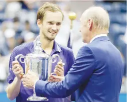  ??  ?? DANIIL MEDVEDEV of Russia (left) is awarded the championsh­ip trophy by tennis legend Stan Smith after defeating Novak Djokovic of Serbia in the US Open men's singles final at the USTA Billie Jean King National Tennis Center on Sept. in New York City. (AFP)