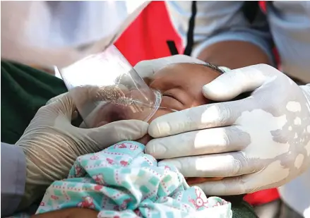  ?? ADI WEDA/ EPA-EFE ?? BAHU-MEMBAHU: Refi, bayi 10 bulan, mendapat perawatan dokter di sebuah rumah sakit darurat di Tanjung, Lombok Utara, kemarin. Foto kiri, tim evakuasi membuka jalan untuk mencari korban di dalam reruntuhan Masjid Jami’an Jamiah, Bangsal, Kecamatan Pamenang, Kabupaten Lombok Utara.