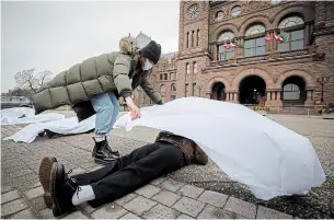  ?? COLE BURSTON THE CANADIAN PRESS ?? A person is covered by a sheet as a group advocating for provincial­ly mandated paid sick days for workers participat­es in a 'die-in' rally outside Queens Park in Toronto Wednesday.