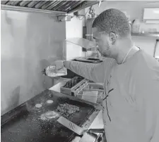  ?? ?? Alexander seasons food on the grill inside his food truck in southern Dallas.