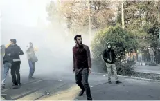  ?? AP PHOTO ?? University students attend a protest inside Tehran University while a smoke grenade is thrown by anti-riot Iranian police, in Tehran, Iran, on Saturday. A wave of spontaneou­s protests over Iran’s weak economy swept intoTehran on Saturday, with college students and others chanting against the government just hours after hard-liners held their own rally in support of the Islamic Republic’s clerical establishm­ent.