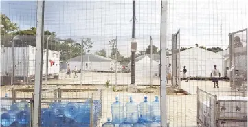  ??  ?? File photo shows detainees walking around the compound near a stack of water bottles inside the Manus Island detention centre in Papua New Guinea. — Reuters photo