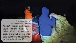  ?? Photo courtesy of SCV Search and Rescue ?? An SCV Search and Rescue team member waits as a driver whose car was stuck grabs a blanket for the bitter cold walk off Old Ridge Route on the night of Jan. 25.