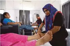  ??  ?? ANISAH (kanan) ketika mengurut kaki di Pusat Orang Buta Tuaran.