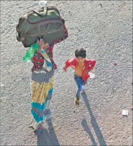  ?? REUTERS ?? ■
Her young son in tow, a migrant worker walks in hope of catching a bus to return to their village, in Ghaziabad on Sunday.