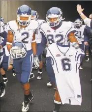  ?? Michael Switzer / Associated Press ?? UConn’s Andre Dixon (2) and Kashif Moore carry the helmet and jersey of slain teammate Jasper Howard in 2009.