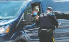  ?? Andrew Vaughan / the cana dian pres ?? A soldier talks with an RCMP officer at a checkpoint in
Portapique, N. S., on Thursday.