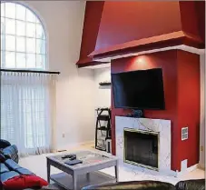  ??  ?? A unique wall treatment around the gas fireplace is accented with bold colors, and an arched window fills the 2-story great room with natural light.