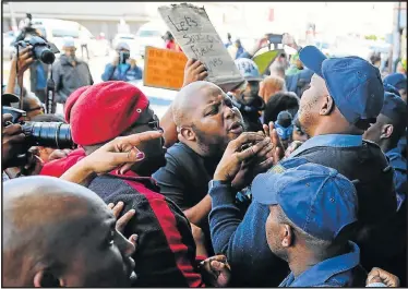  ?? Picture: WERNER HILLS ?? HEATED EMOTIONS: ANC Youth League regional secretary Luyolo Nqakula tries to put across his point to police officials at the door of the Jesus Dominion Internatio­nal church during the protest on Sunday