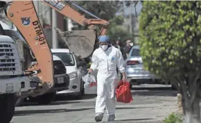  ?? FERNANDO LLANO/AP ?? An investigat­or carries equipment May 20 outside the house where police found bone fragments in the State of Mexico.