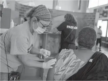  ?? JOAO SILVA/THE NEW YORK TIMES ?? Nurse Jacqui Dallimore administer­s a dose of the Johnson & Johnson coronaviru­s vaccine in December as part of a drug trial at the Desmond Tutu HIV Foundation Youth Center in Masiphumel­ele, South Africa.