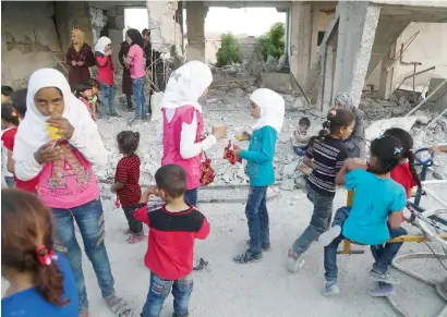  ?? AFP ?? Syrian children, who fled their homes in Ghouta’s Al Marj town, play amid the debris of buildings in the town of Al Nashabiyah in the eastern Ghouta region, a rebel stronghold east of the capital Damascus. —