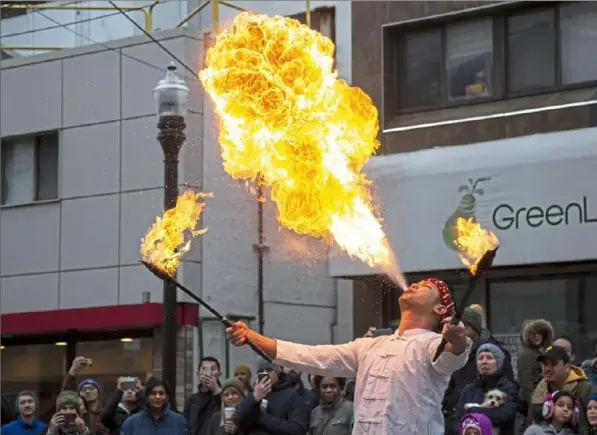  ?? Jessie Wardarski/Post-Gazette ?? Eakkapab Boonsombat of Squirrel Hill, originally from Thailand, breathes fire into the sky Sunday as an intrigued parade audience watches during the Chinese Lunar New Year Parade in Squirrel Hill.