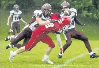  ?? JULIE JOCSAK/POSTMEDIA NETWORK ?? Brock Benevento of the Denis Morris Redmen and Ryan Giles and Riley Hart of the Saint Michael Mustangs tangle in high school football action at Denis Morris in St. Catharines Thursday.