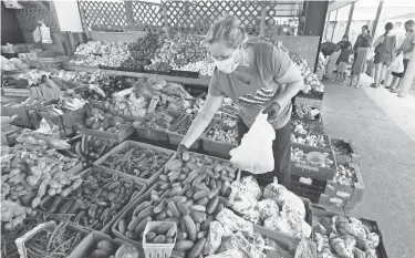  ??  ?? Fadila Botic wears a protective mask and gloves as she makes her selections at the Jacksonvil­le Farmers Market March 25. BOB SELF/USA TODAY NETWORK