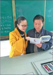  ?? PROVIDED TO CHINA DAILY ?? Jiang Lili and her father Jiang Congqing discuss teaching in a classroom of Qingxi Primary School in Yongjiang county, Hunan province.