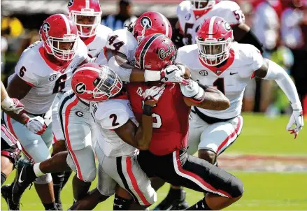  ?? CURTIS COMPTON / CCOMPTON@AJC.COM ?? Georgia defensive players Richard LeCounte (left) and Juwann Taylor are the first to arrive to gang tackle South Carolina running back Rico Dowdle for a loss during the first half of the Bulldogs’ 41-17 victory over the Gamecocks on Saturday.