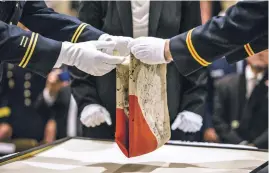  ??  ?? A Japanese good-luck flag that hung for years at the New Mexico Military Museum is folded during a repatriati­on event Saturday in which the Obon Society took possession of the World War II-era banner.