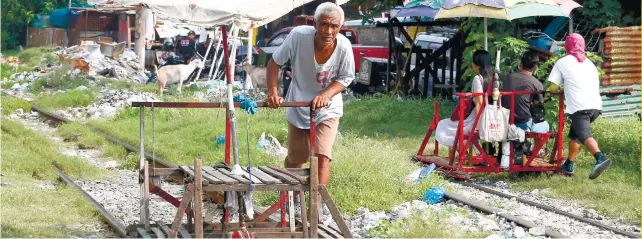  ??  ?? OPTION: Enterprisi­ng residents use improvised “trolleys” using the railroad tracks. With Metro Manila’s traffic congestion, the “trolleys’ provide a cheaper alternativ­e. AP FOTO