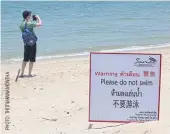  ??  ?? LEFTA sign in Thai, Chinese and English warns tourists to avoid swimming on Sai Noi Beach in Hua Hin, where a tourist was bitten by a bull shark earlier this year.