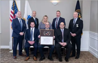  ?? COURTESY CHELMSFORD POLICE DEPARTMENT ?? Chelmsford Police Chief Colin Spence, seated at center, holds a plaque signifying that the Chelmsford Police Department was once again accredited by the Massachuse­tts Police Accreditat­ion Commission as members of the department and MPAC stand by.