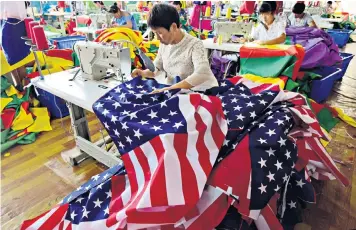  ??  ?? Chinese workers sewing US flags at a factory in Anhui province. Trump might have been more effective had he worked with US allies